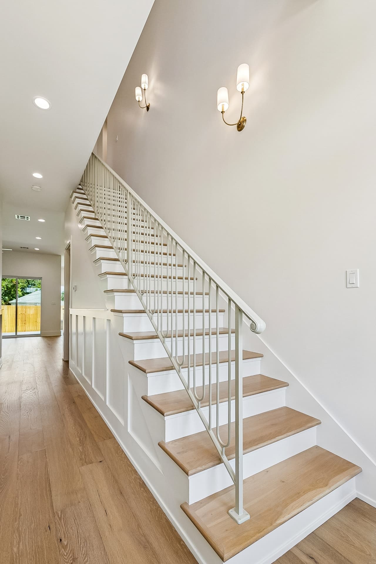 Staircase with brass sconces and white paneling