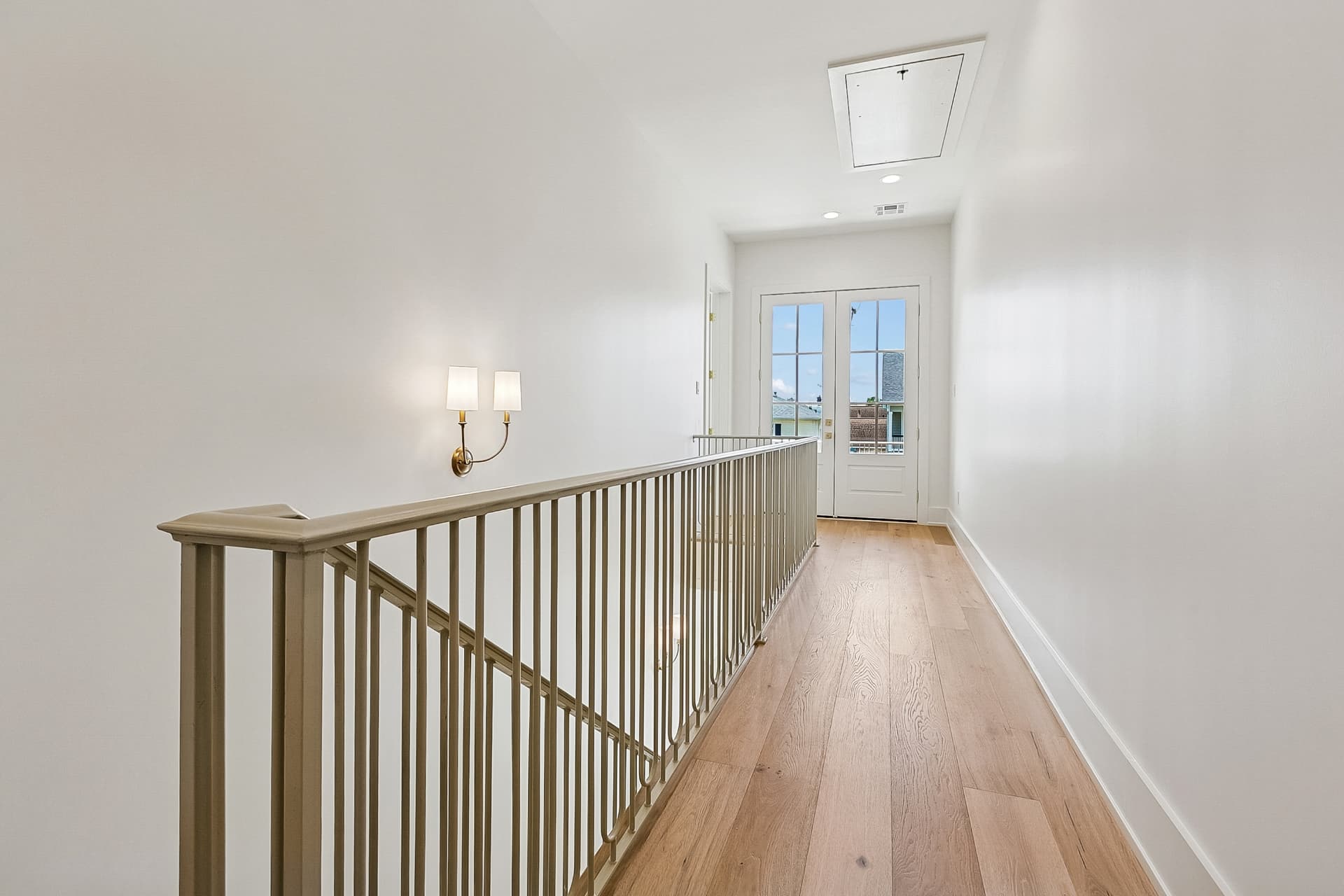 Upstairs hallway with iron railing and French doors
