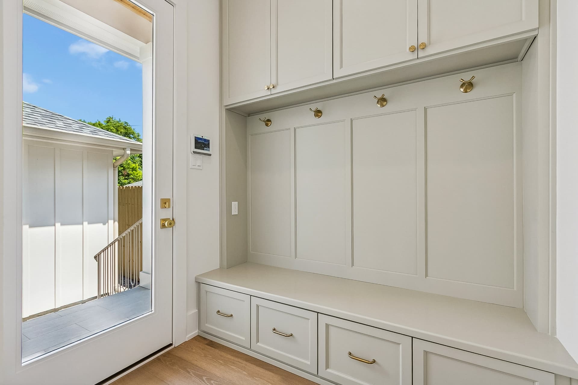 Mudroom with built-in bench, hooks, and cabinets