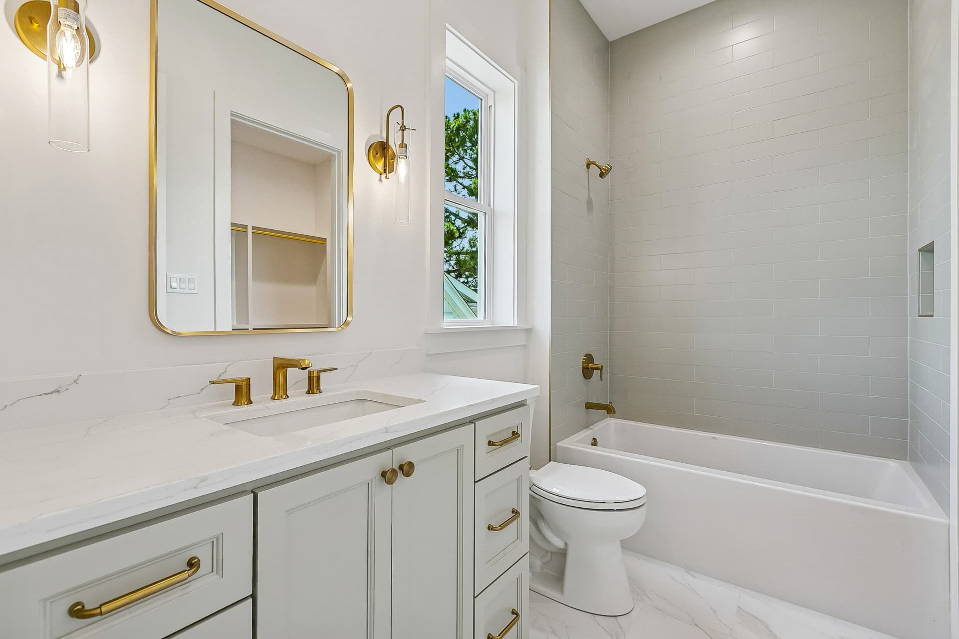 Hall bathroom with tub and gold fixtures